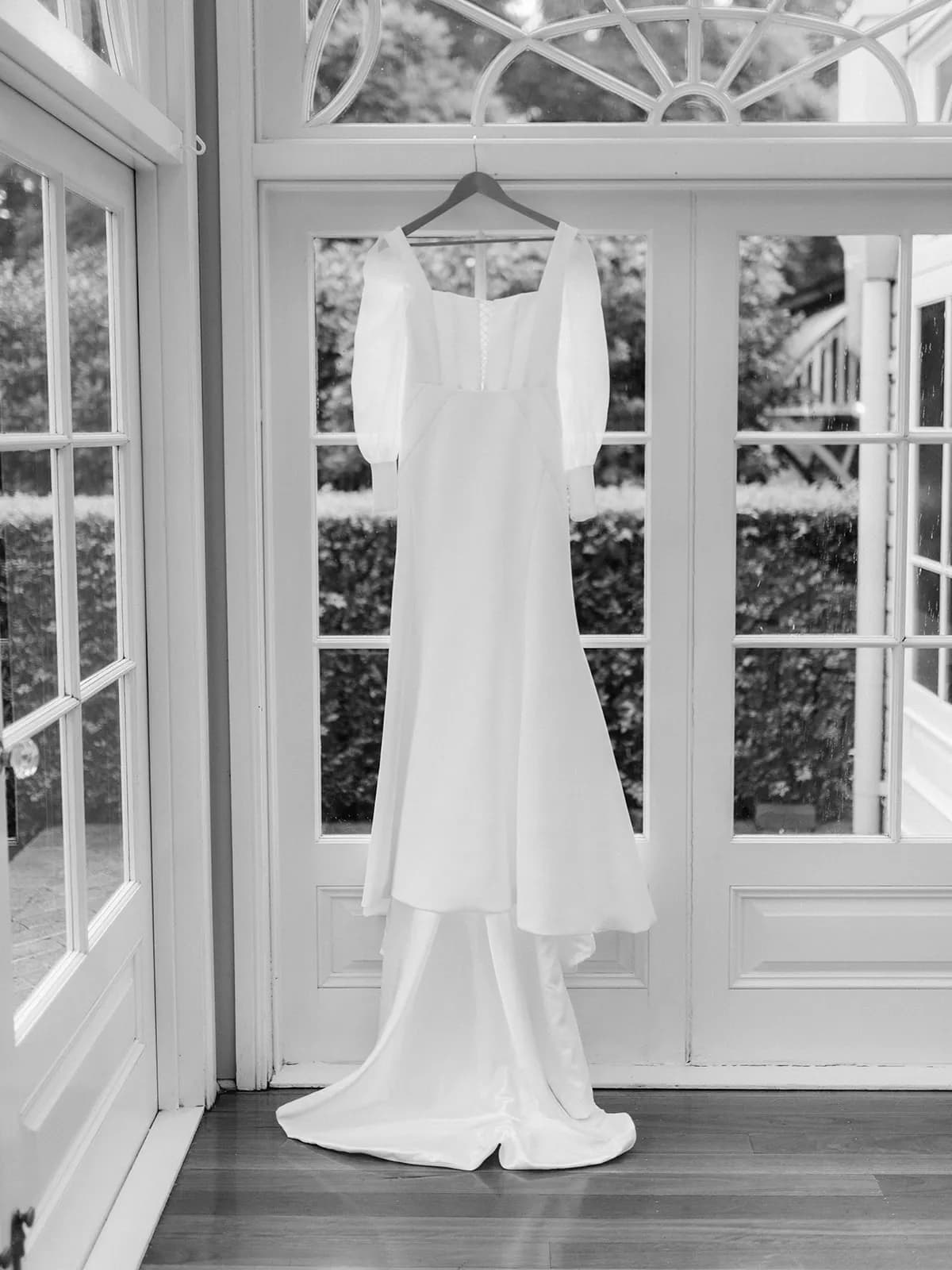 Weddimg dress hanging in front of french doors