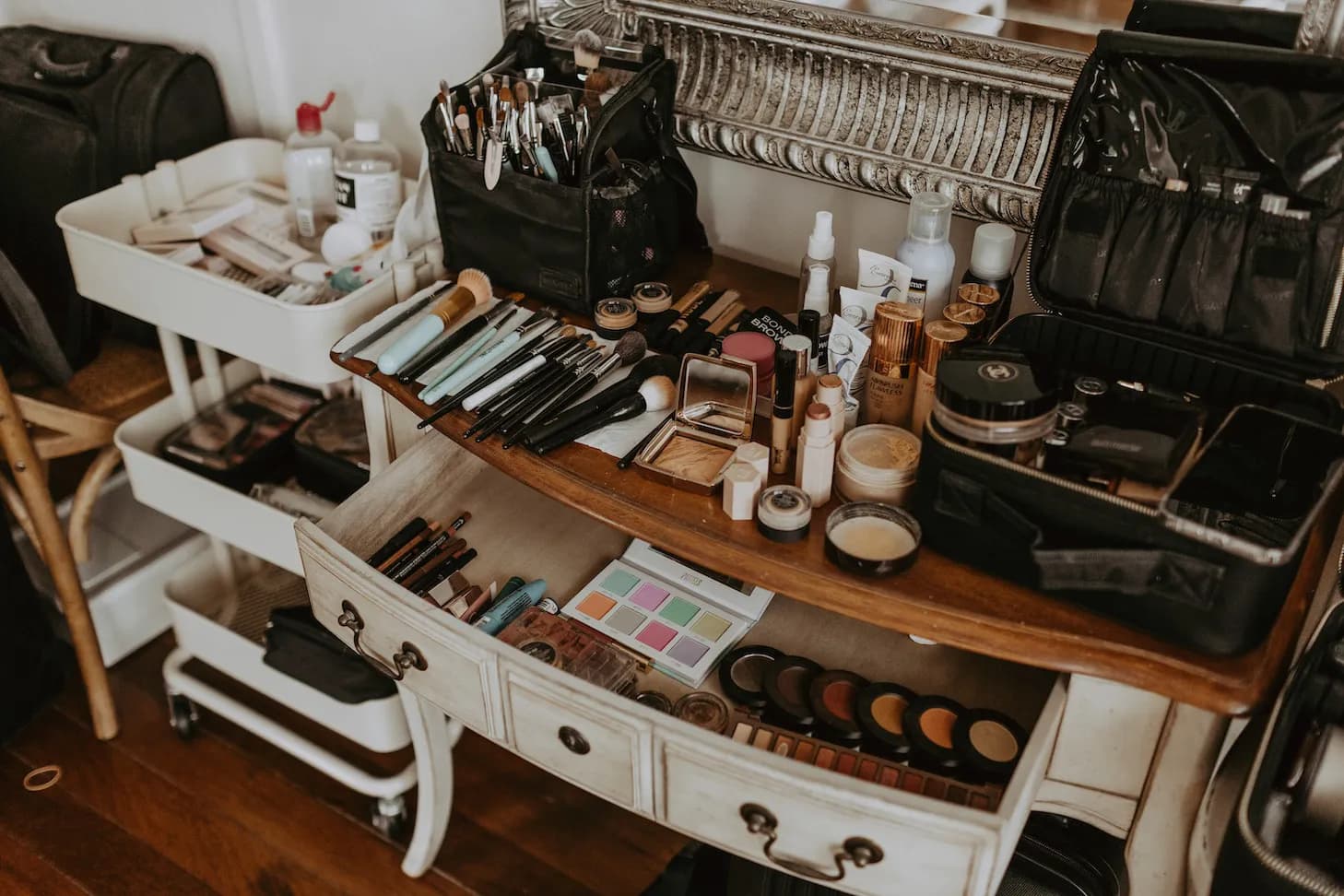 Console table covered with brushes, lipstick, and makeup