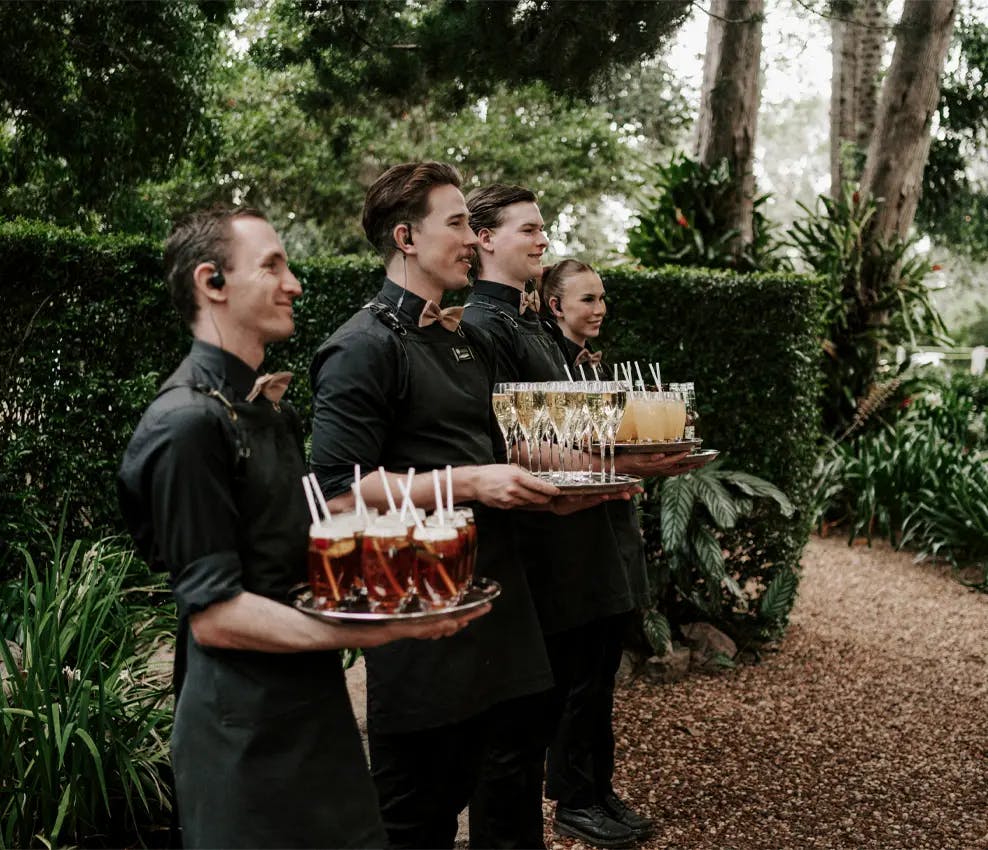 Waiters line up with trays of drinks
