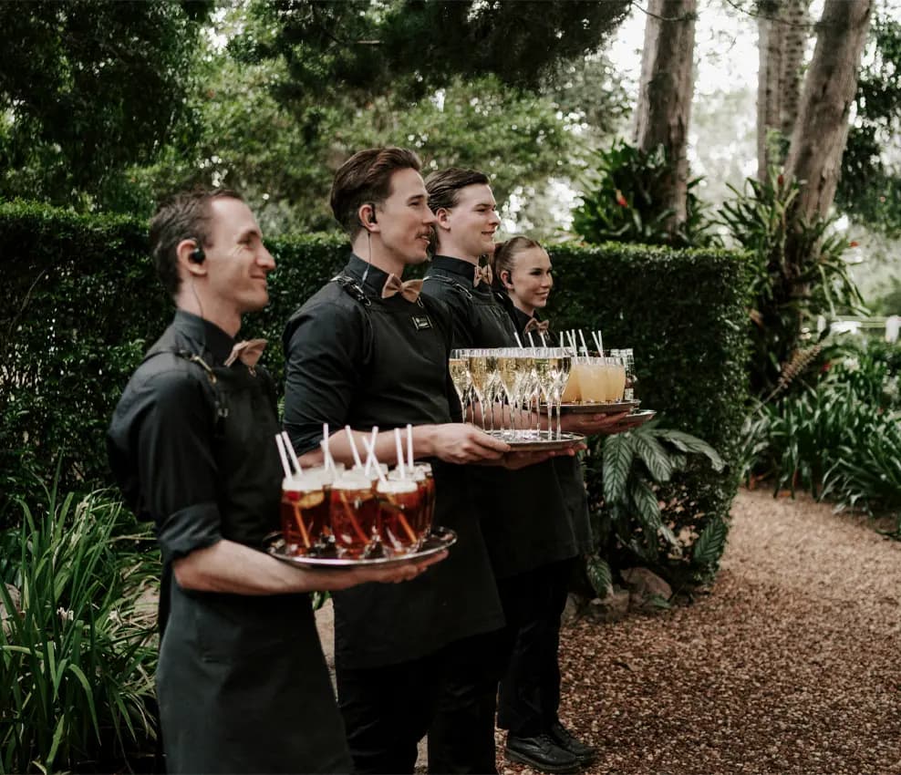 Waiters line up with trays of drinks