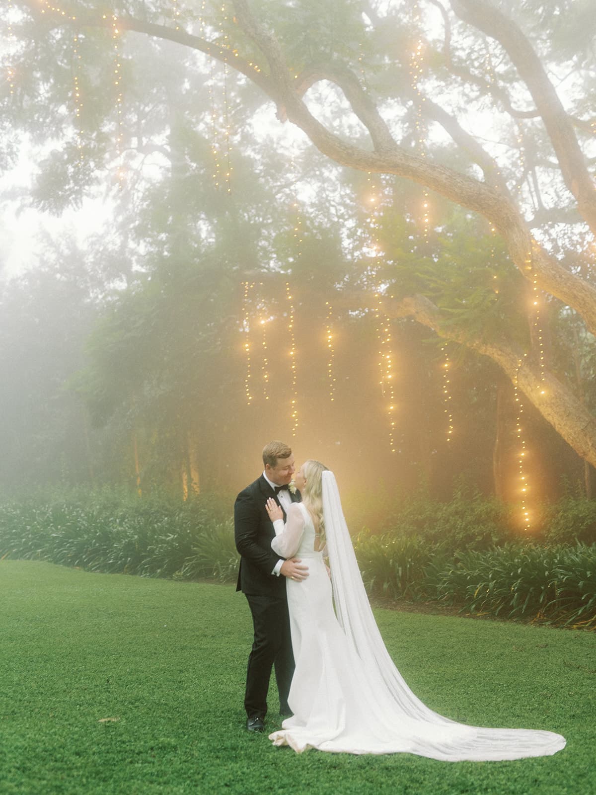 Bride and groom kissing under fairy lights