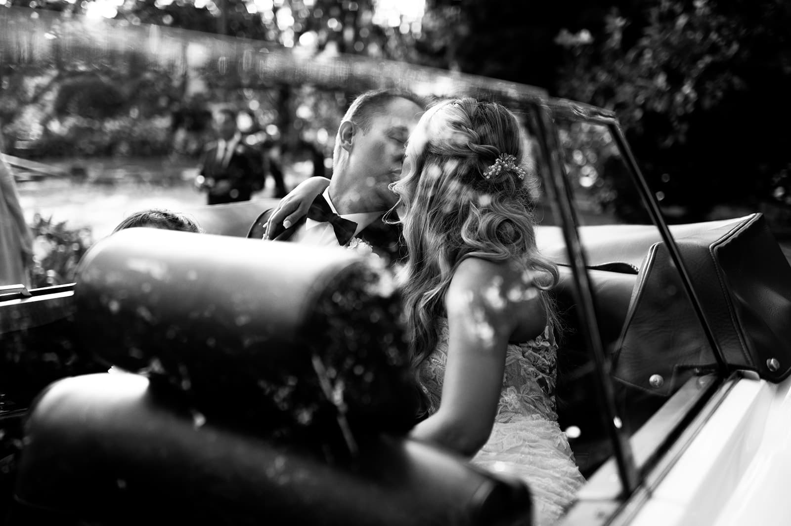Bride and groom kissing in car