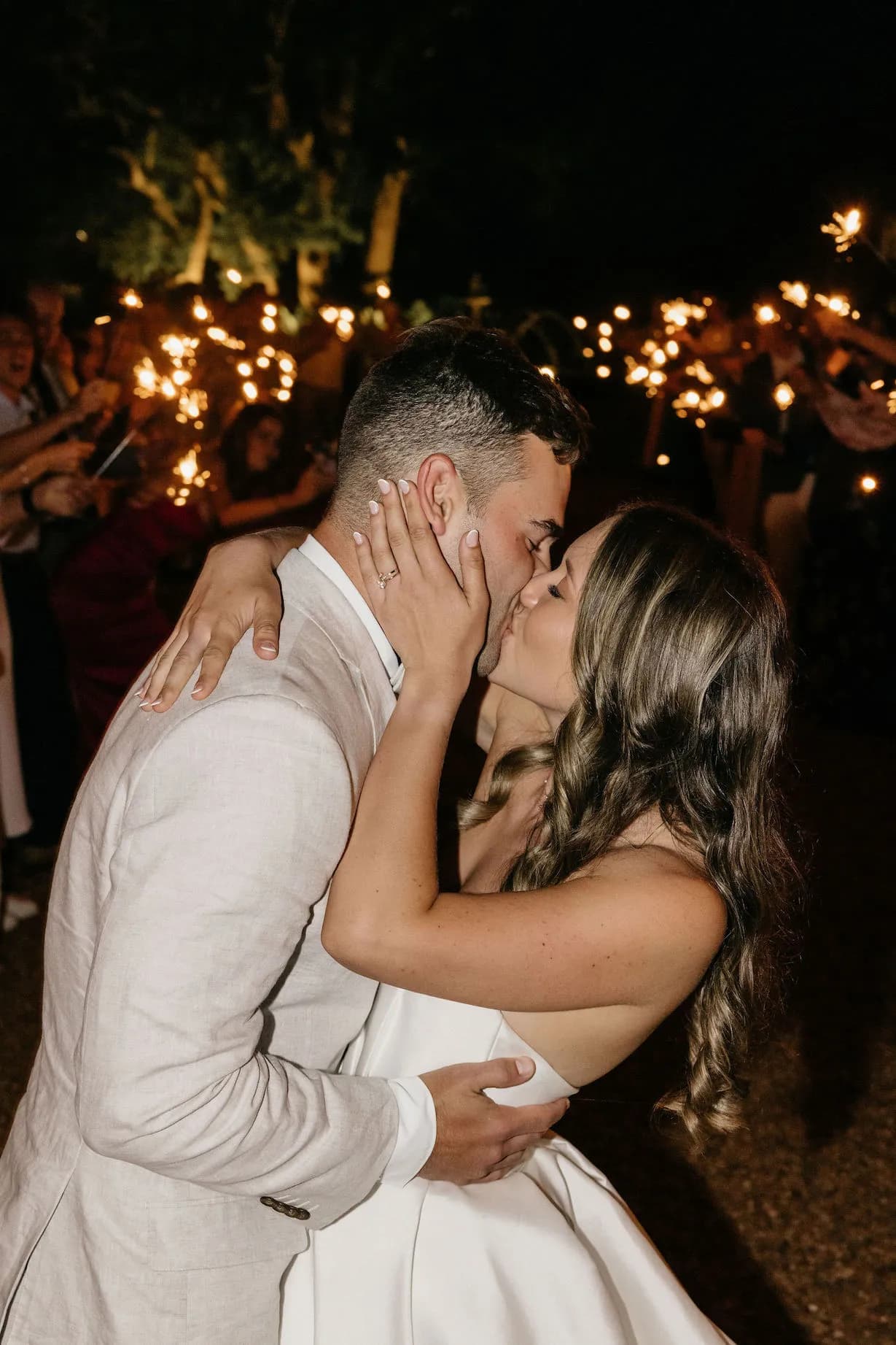 Bride and groom kissing with sparklers in background