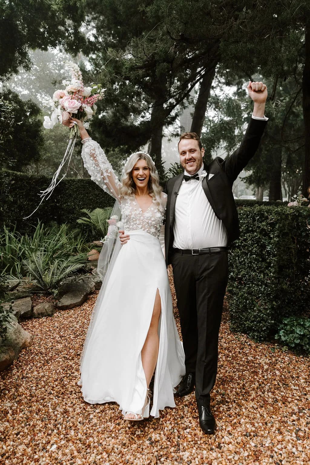 Bride and groom celebrating and holding bouquet in the air
