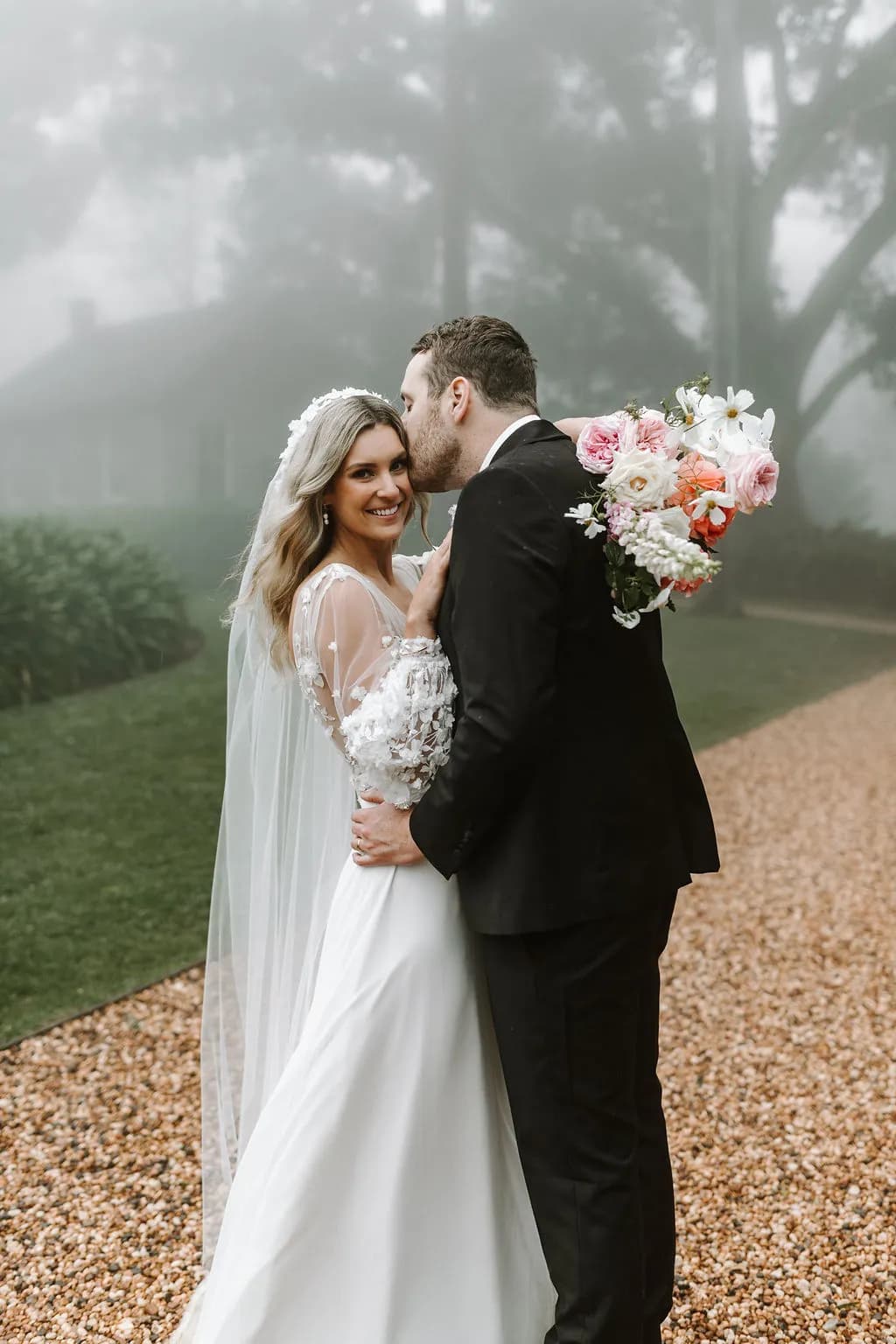 Bride and groom kissing holding bouquet