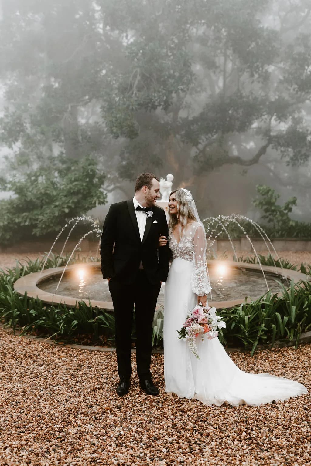 Bride and groom standing in front to fountain