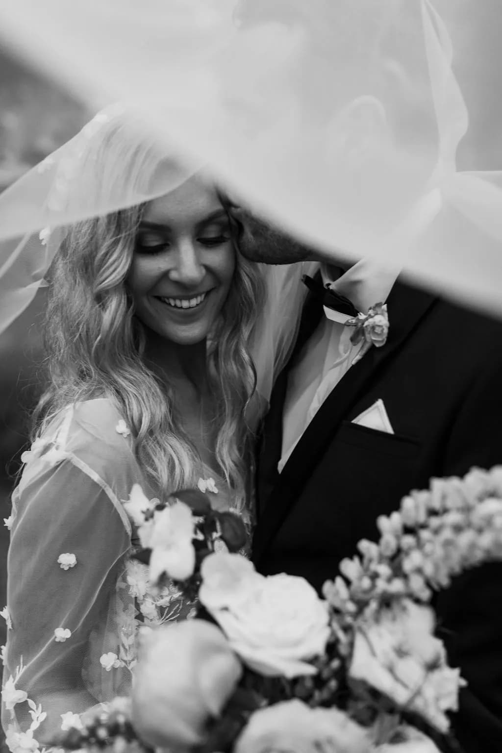 Bride and groom kissing under veil