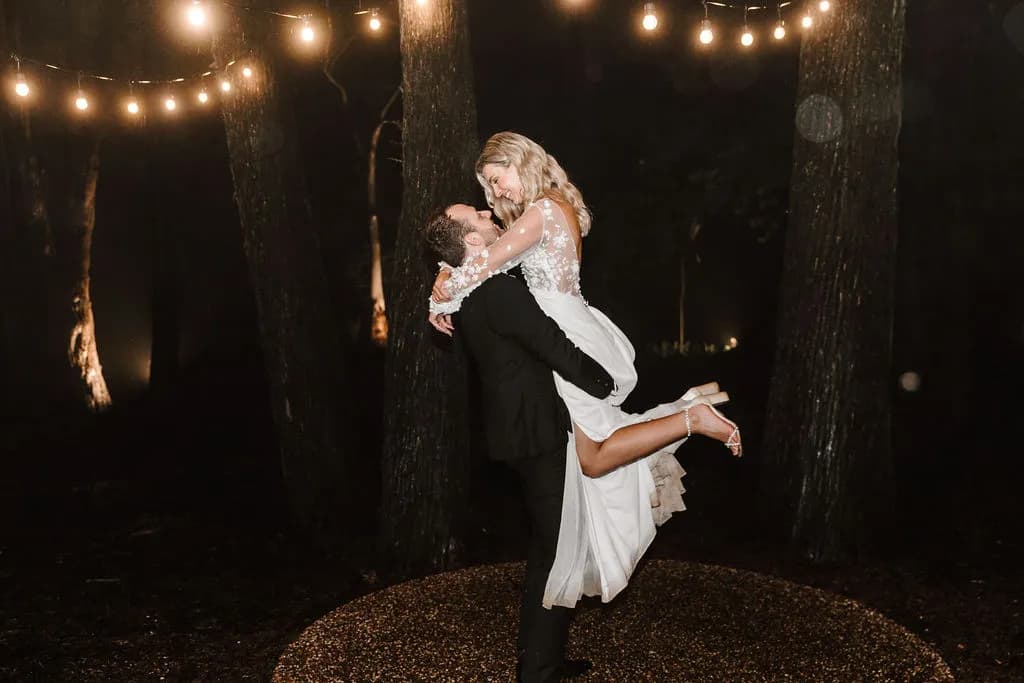 Bride and groom dancing outside under festoon lights