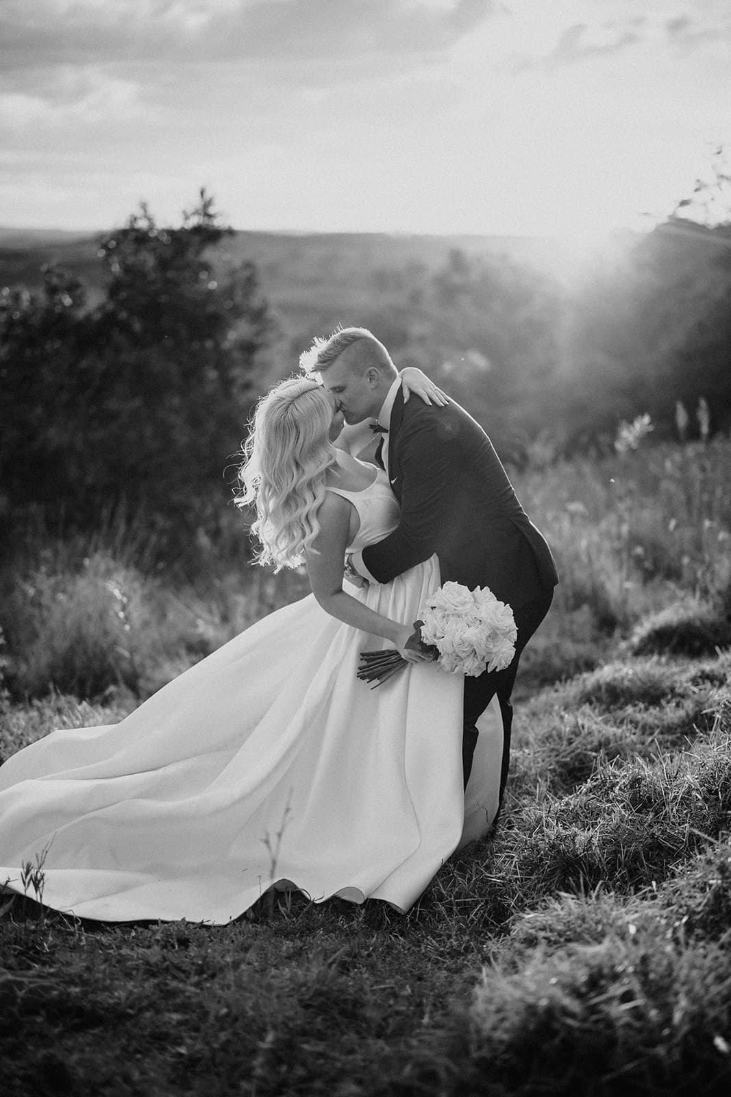 Bride and groom kissing in field