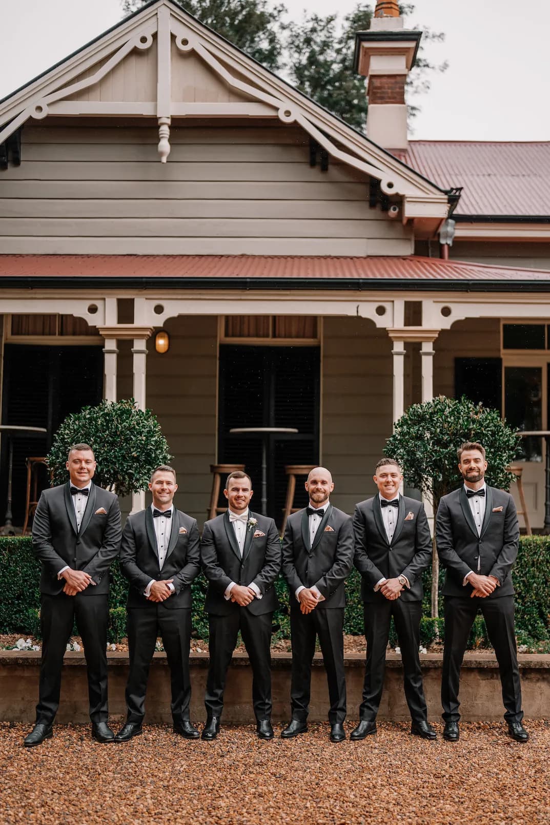 Groom and groomsmen standing in front of homestead