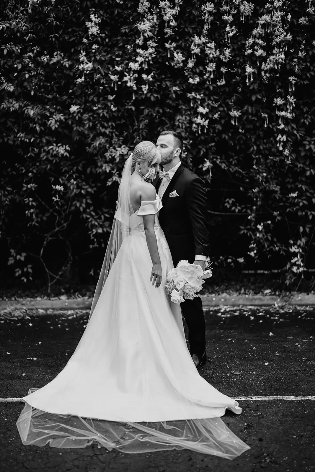 Bride and groom kissing on tennis court