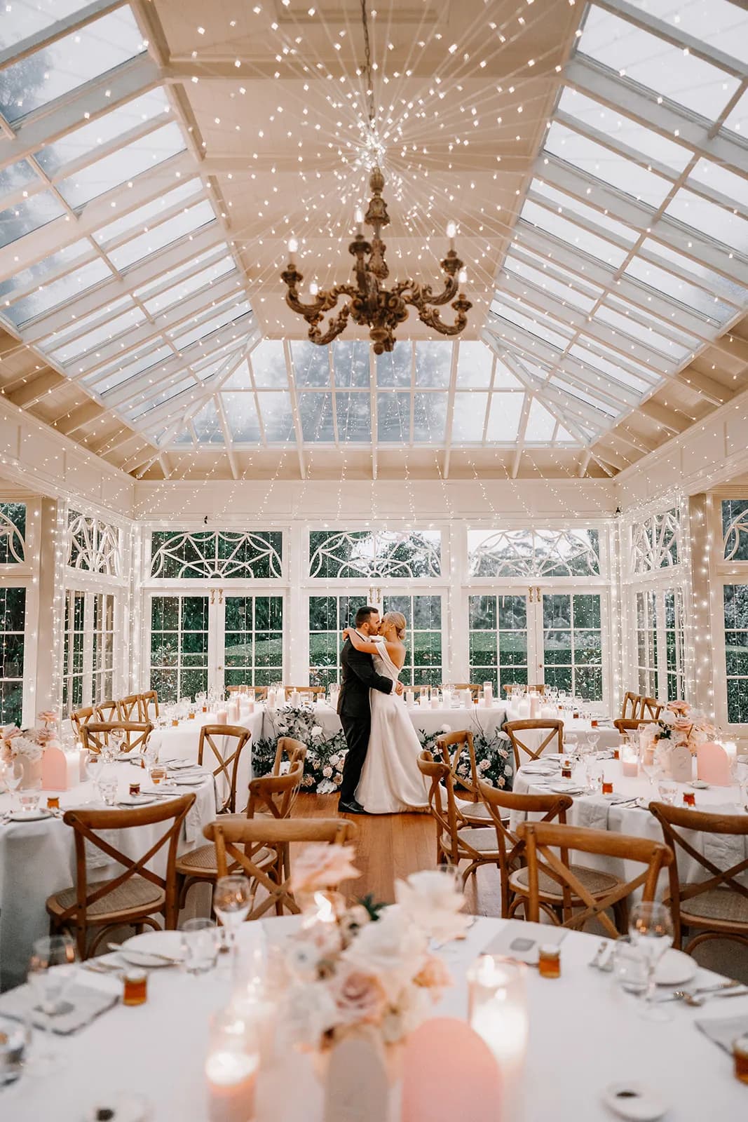 Bride and groom kissing in wedding reception with fairylights