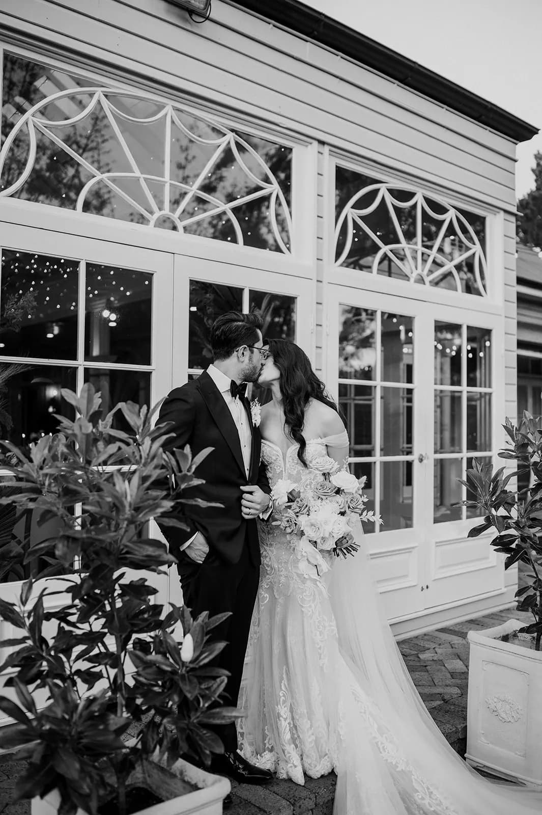 a black and white photograph of a happy couple kissing on their wedding day outside the gabbinbar wedding venue