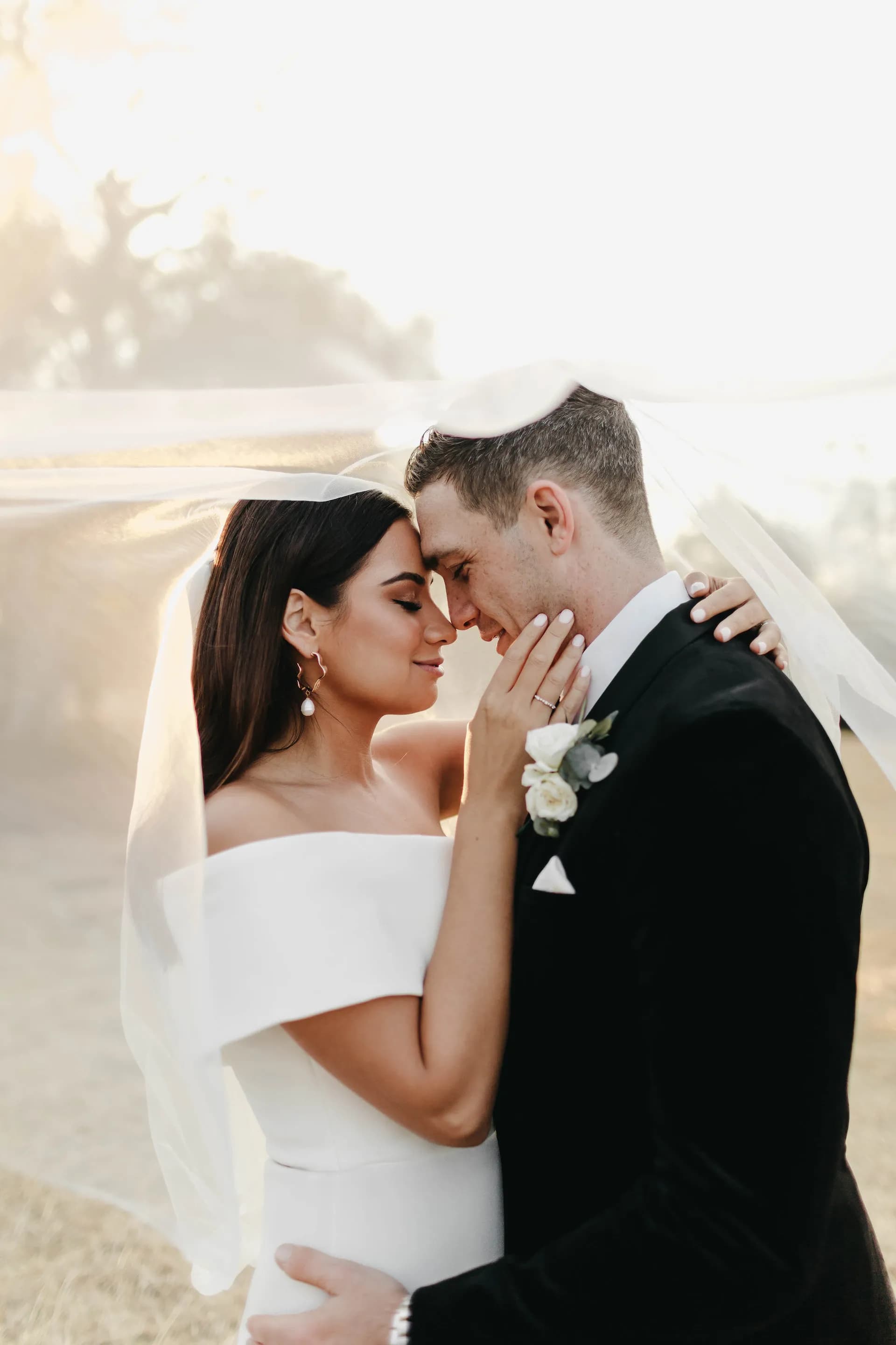 Bride and groom holding each other under veil
