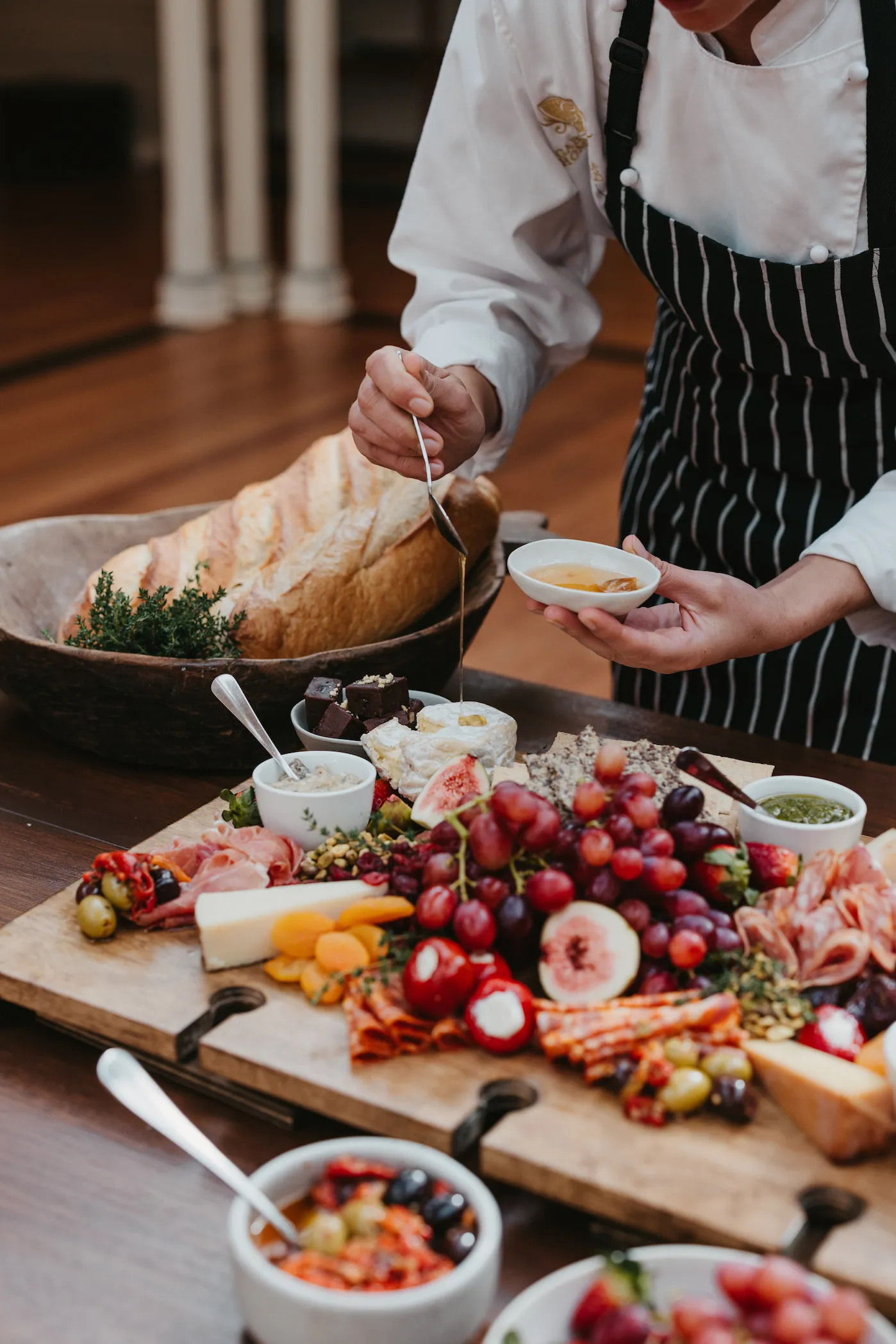 Person putting honey on charcuterie board
