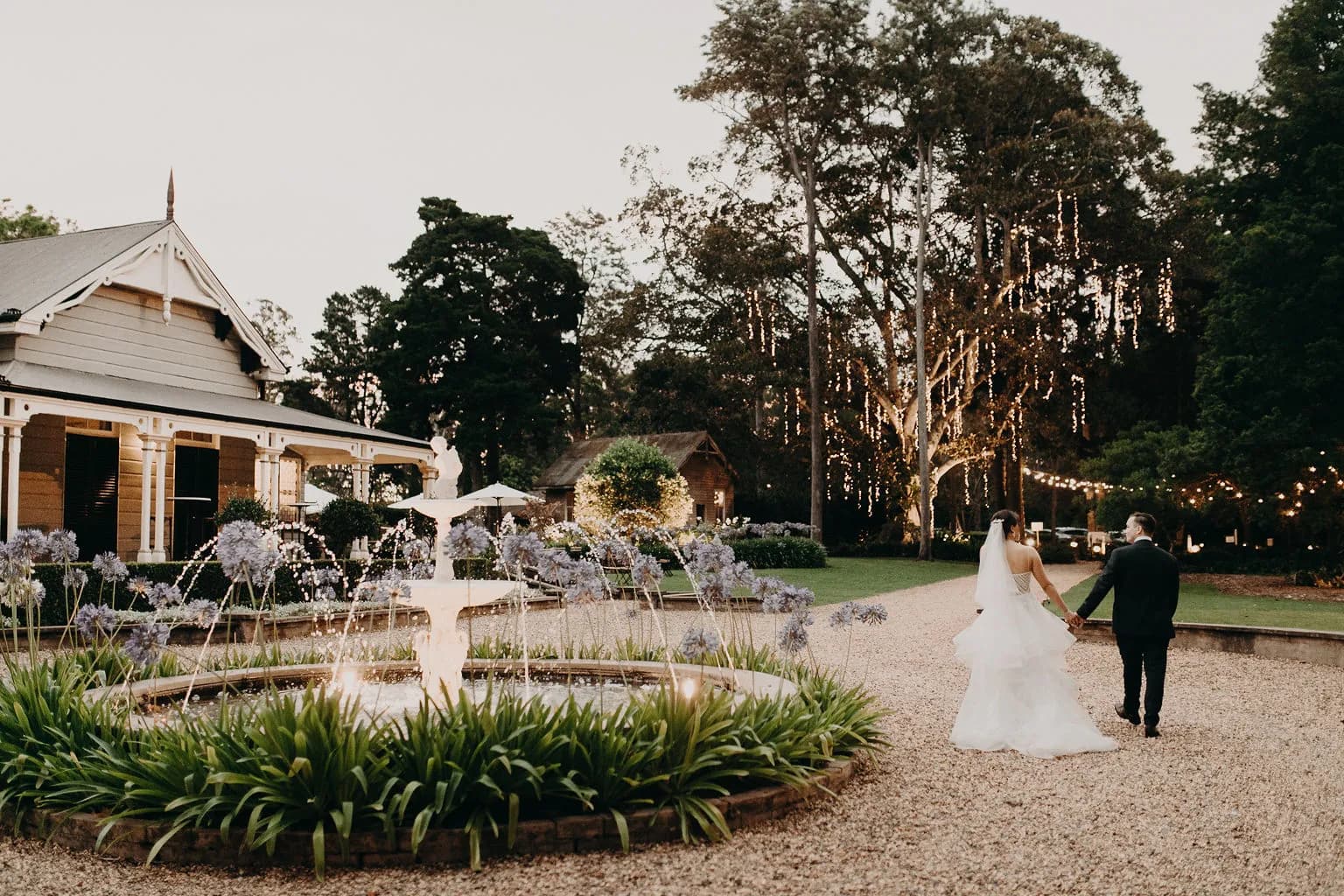 Bride and groom walking down stone driveway holding hands