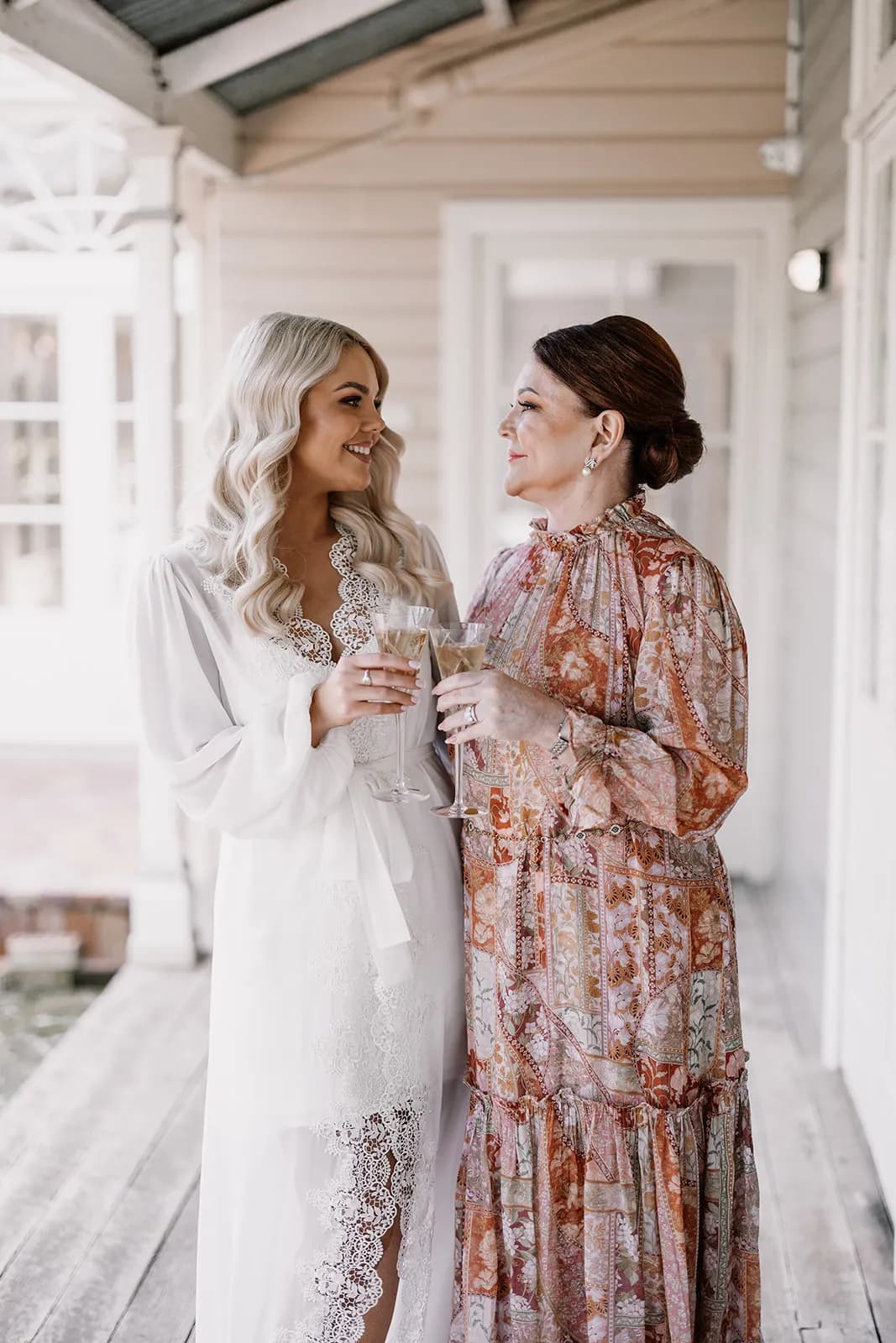Bride looking at mother holding glass of champagne