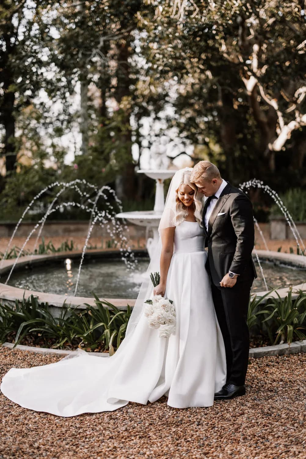 Bride and groom standing in front of fountain
