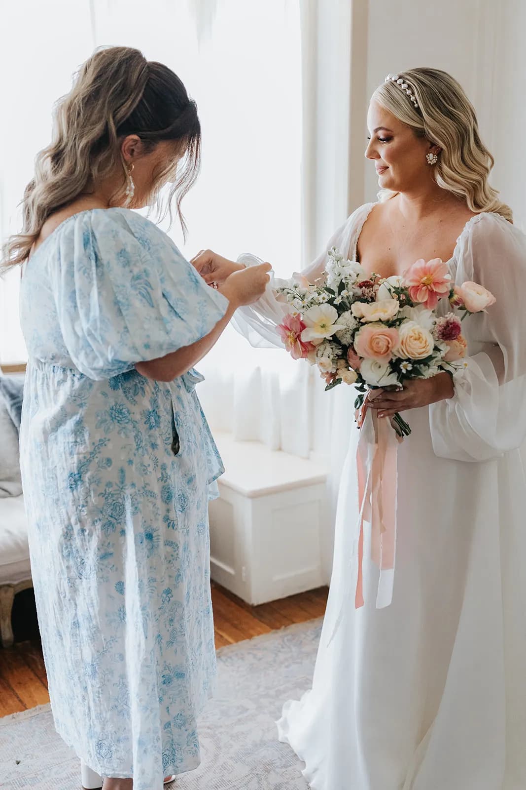 Bridesmaid helping bride with dress