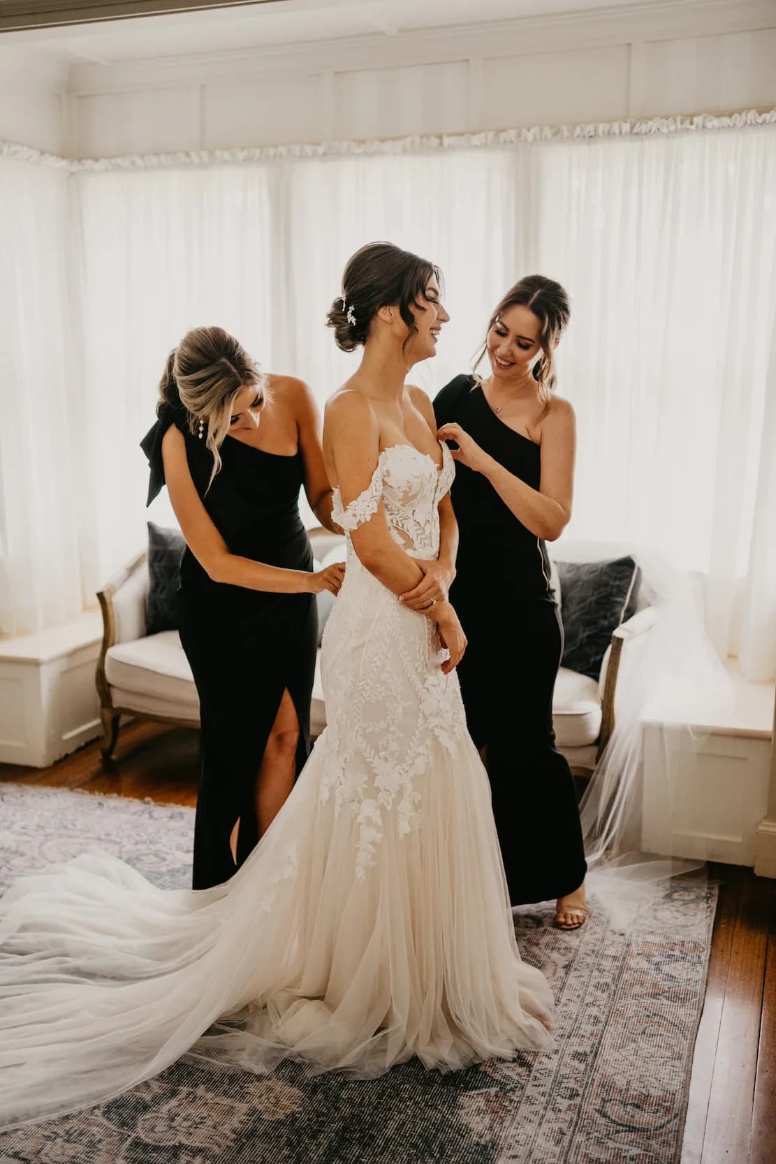 Bridesmaids helping bride get dressed